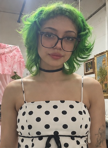 Portrait with green hair, glasses, and a black-and-white polka-dot dress.